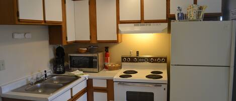 Une cuisine avec des meubles de rangement en bois, un four à micro-ondes, une cuisinière et un réfrigérateur.
