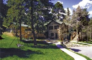 A stone cabin with a porch, surrounded by trees and a picnic table. - Meadow Creek Mountain Lodge and Event Center (Pine)