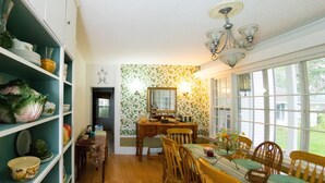 Un comedor con una mesa y sillas de madera, una estantería con diversos objetos, y una ventana que ofrece vistas al exterior.