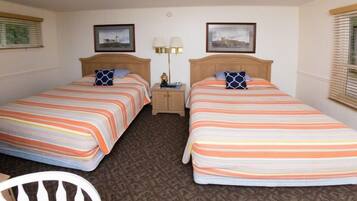 A hotel room with two single beds, a nightstand with lamps, and a chair.