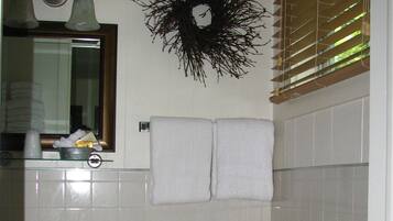 Un baño con lavamanos, espejo, perchero para toallas y una guirnalda decorativa en la pared.