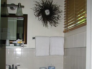 Une salle de bain équipée d’un lavabo, d’un miroir, d’un porte-serviettes et d’une guirlande décorative accrochée au mur.