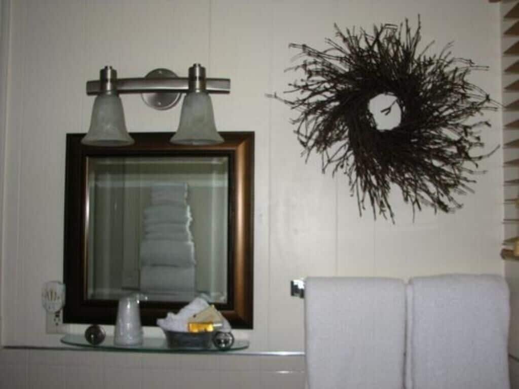 A bathroom with a framed mirror, two wall-mounted lights, and a decorative wreath.