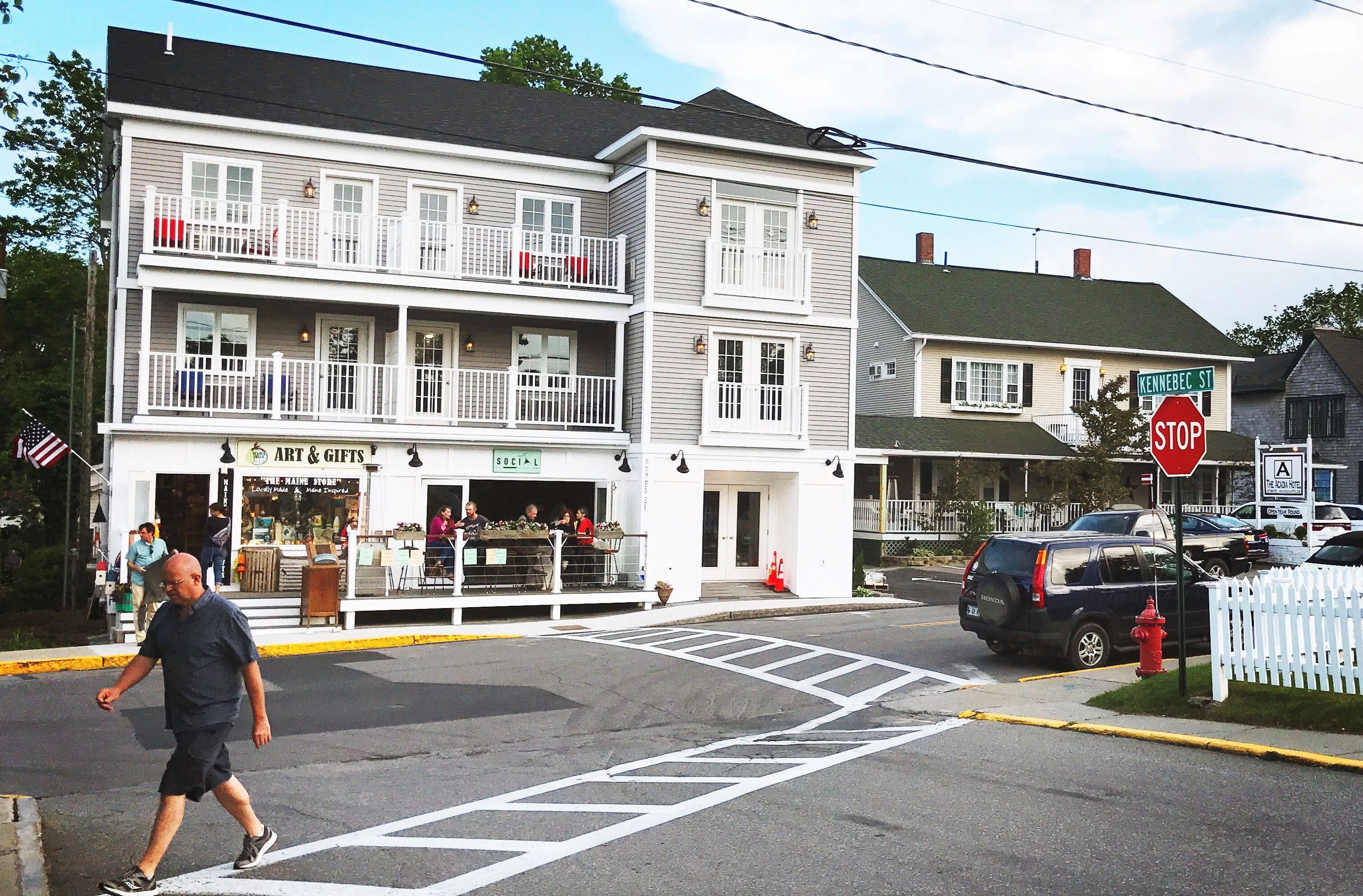 A two-story building with a balcony, a stop sign, and a street intersection.