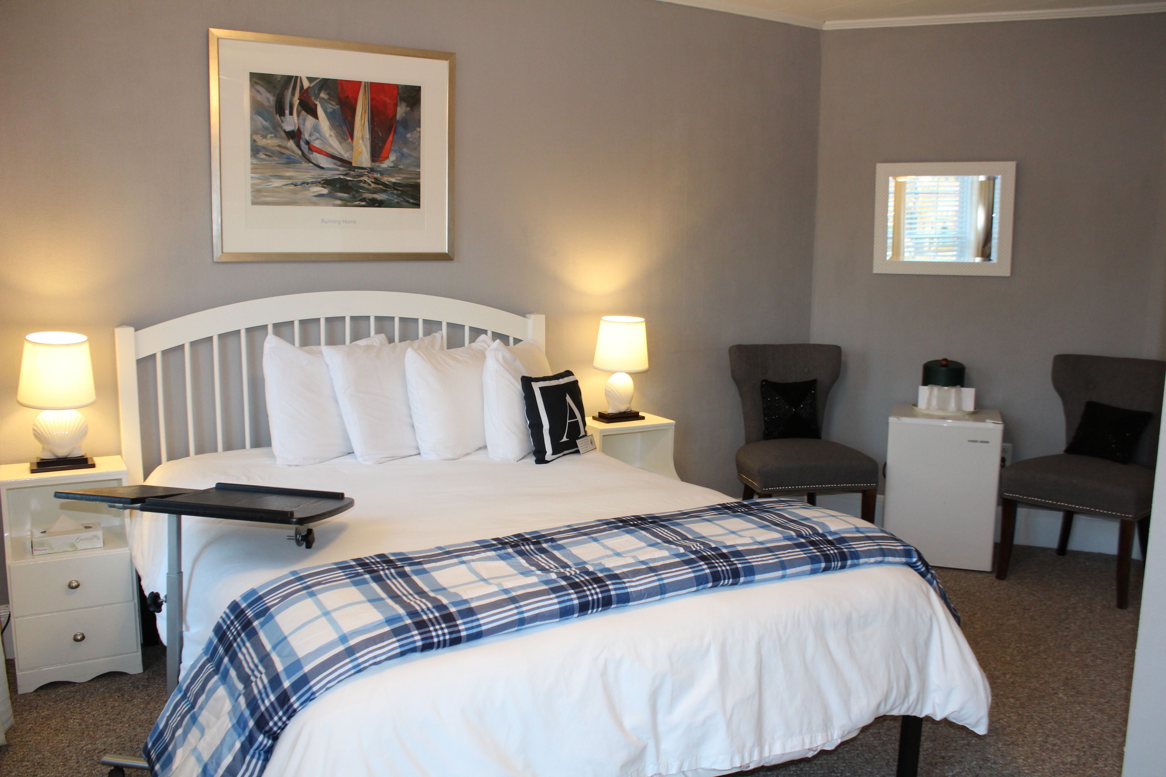 A hotel room with a bed, nightstands, a chair, a small table, and a wall-mounted picture.
