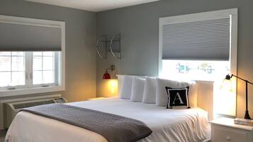 Une chambre bien rangée, avec un grand lit, des tables de chevet, un radiateur et une fenêtre équipée de stores.