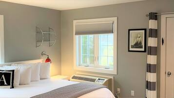 A bedroom with a bed, a bedside table, a lamp, a radiator, and a window with a view of trees.
