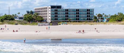Una playa con un edificio moderno al fondo.