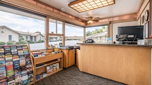 A reception area with a wooden counter, a computer, and a view of the outside.