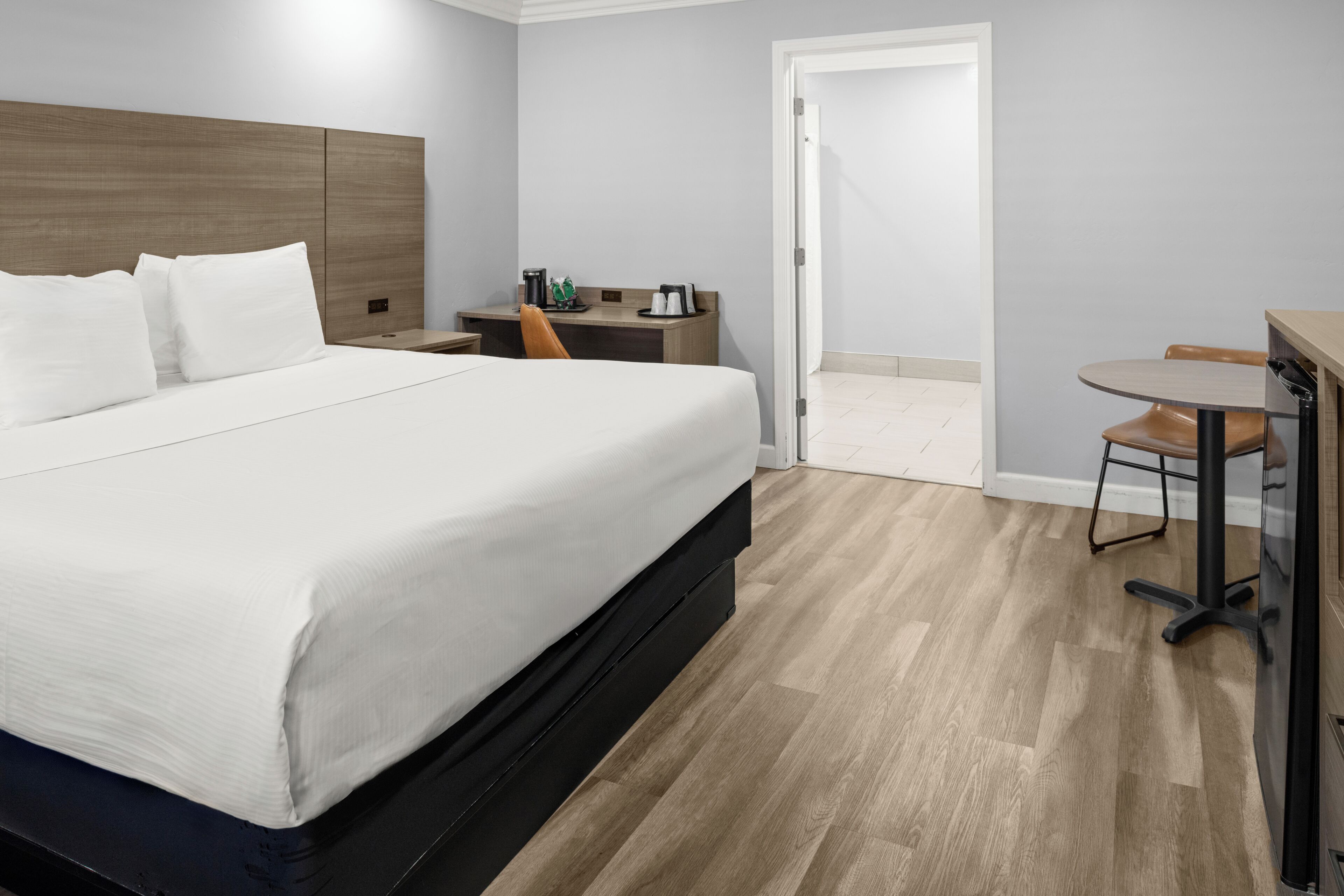 A hotel room with a bed, a desk, a chair, and a table.