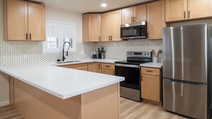 A modern kitchen with wooden cabinets, a stainless steel refrigerator, a microwave, and a built-in oven.