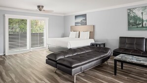 A bedroom with a bed, a sofa, a chair, and a table.