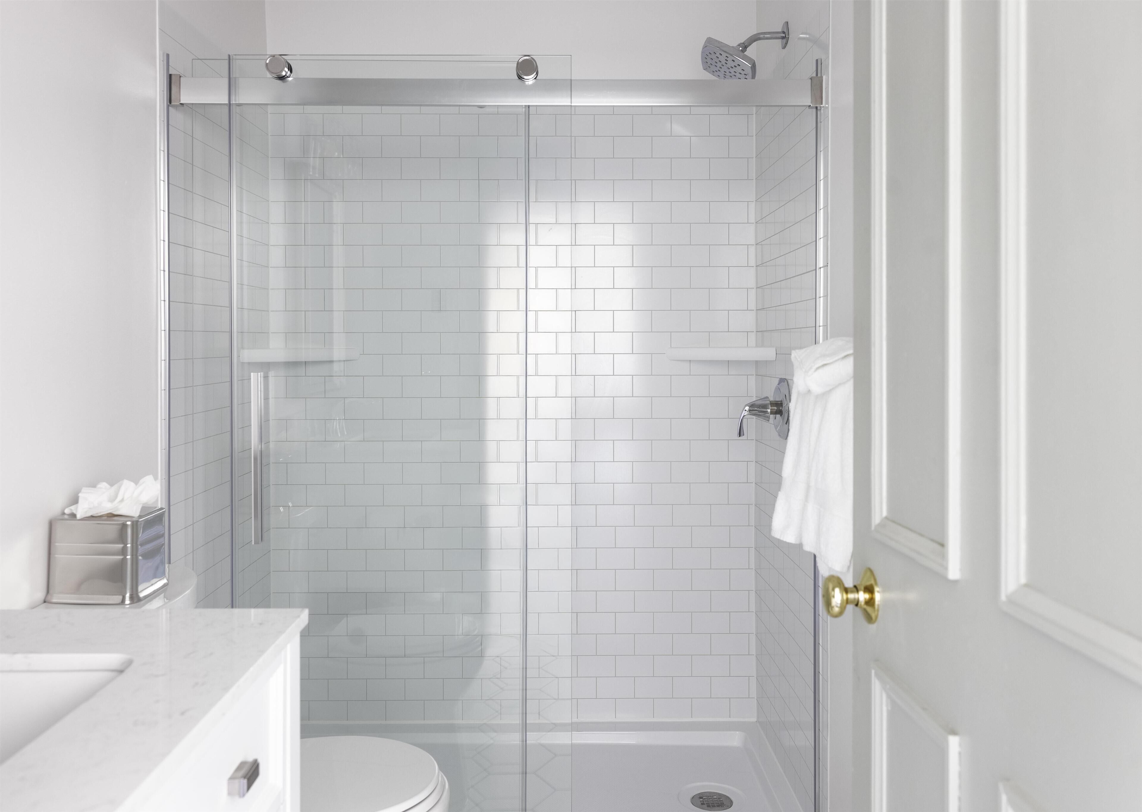 A modern bathroom with white subway tiles, a glass-enclosed shower, a toilet, and a marble countertop.