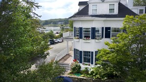 A two-story house with a balcony, surrounded by trees and a view of a lake. - Kennebunkport Inn (Kennebunkport)
