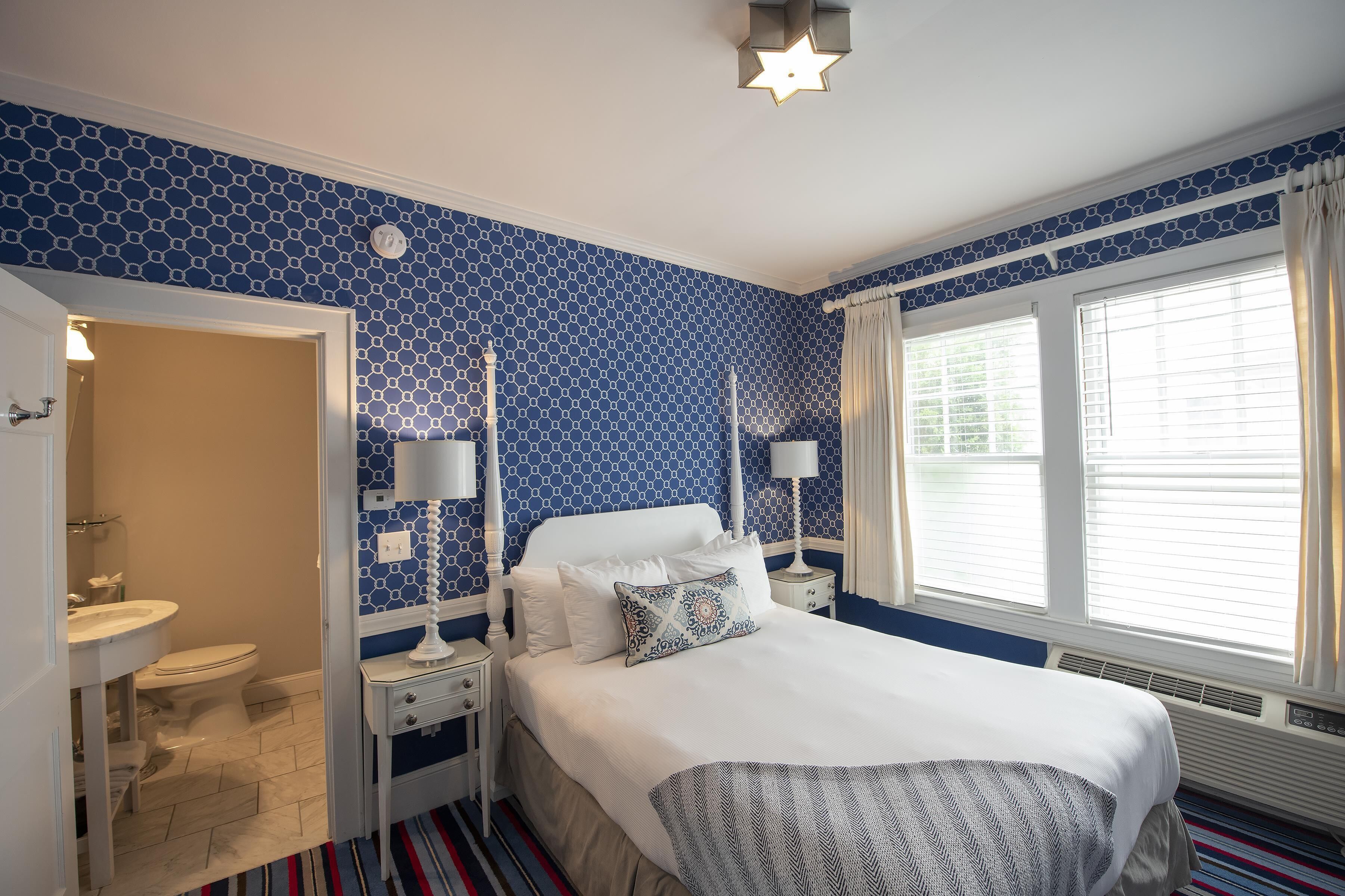A bedroom with a bed, nightstands, a dresser, and a window with curtains.