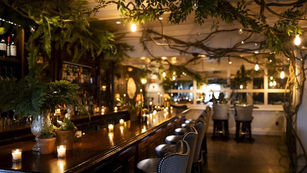 A bar area with a long counter, potted plants, and candles. - Kennebunkport Inn (Kennebunkport)