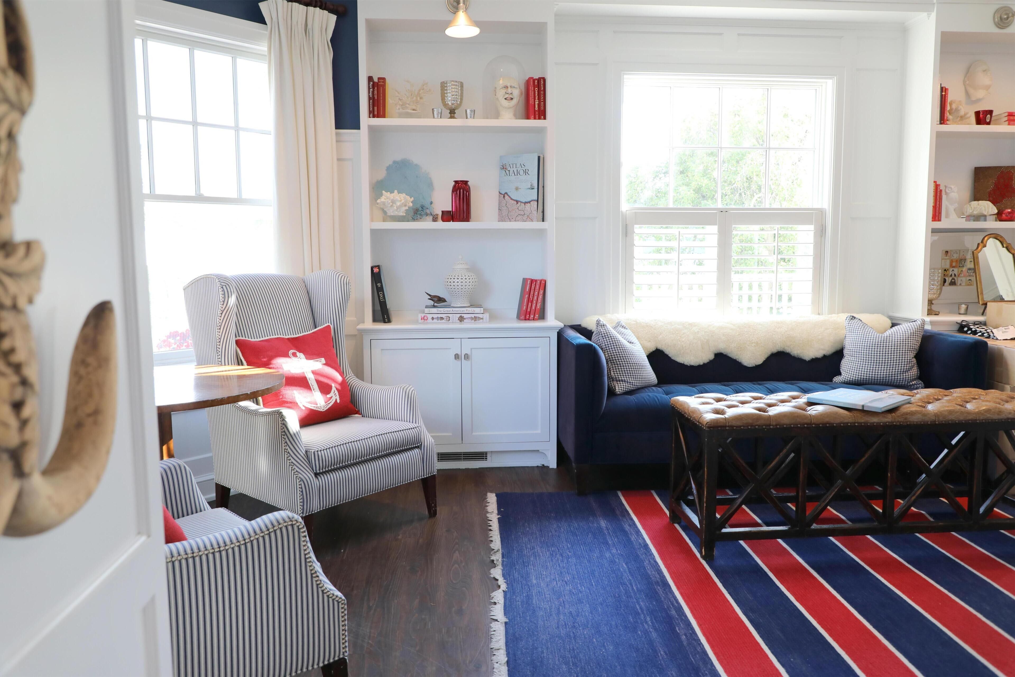 A living room with striped chairs, a blue sofa, a wooden coffee table, and a bookshelf with decorative items.