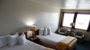 A hotel room with two beds, a chair, a small table, and a window with curtains. - Knights Inn Boardman (Boardman)