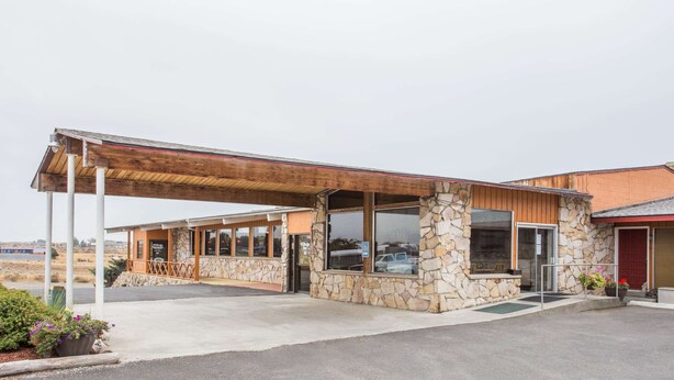 A building with a stone facade, wooden exterior, and a covered entrance area. - Knights Inn Boardman (Boardman)