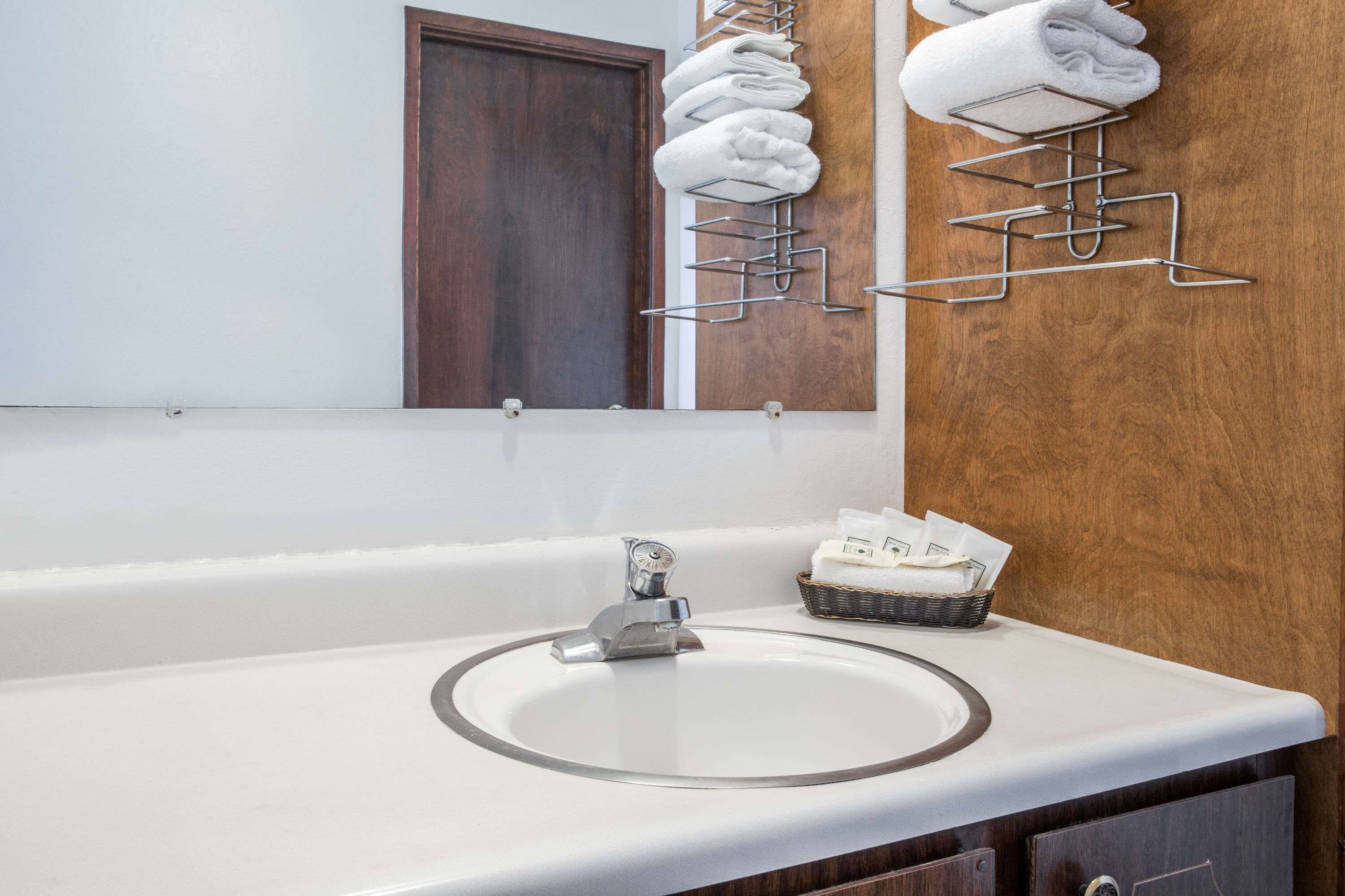 A bathroom with a white sink, a mirror, and a towel rack with folded towels.