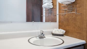 A bathroom with a white sink, a mirror, and a towel rack with folded towels.