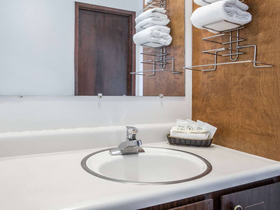 A bathroom with a white sink, a mirror, and a towel rack with folded towels.