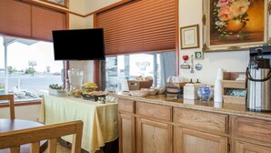 A cafe with a wooden counter, a television mounted above it, and a window with a view of the street. - Knights Inn Boardman (Boardman)