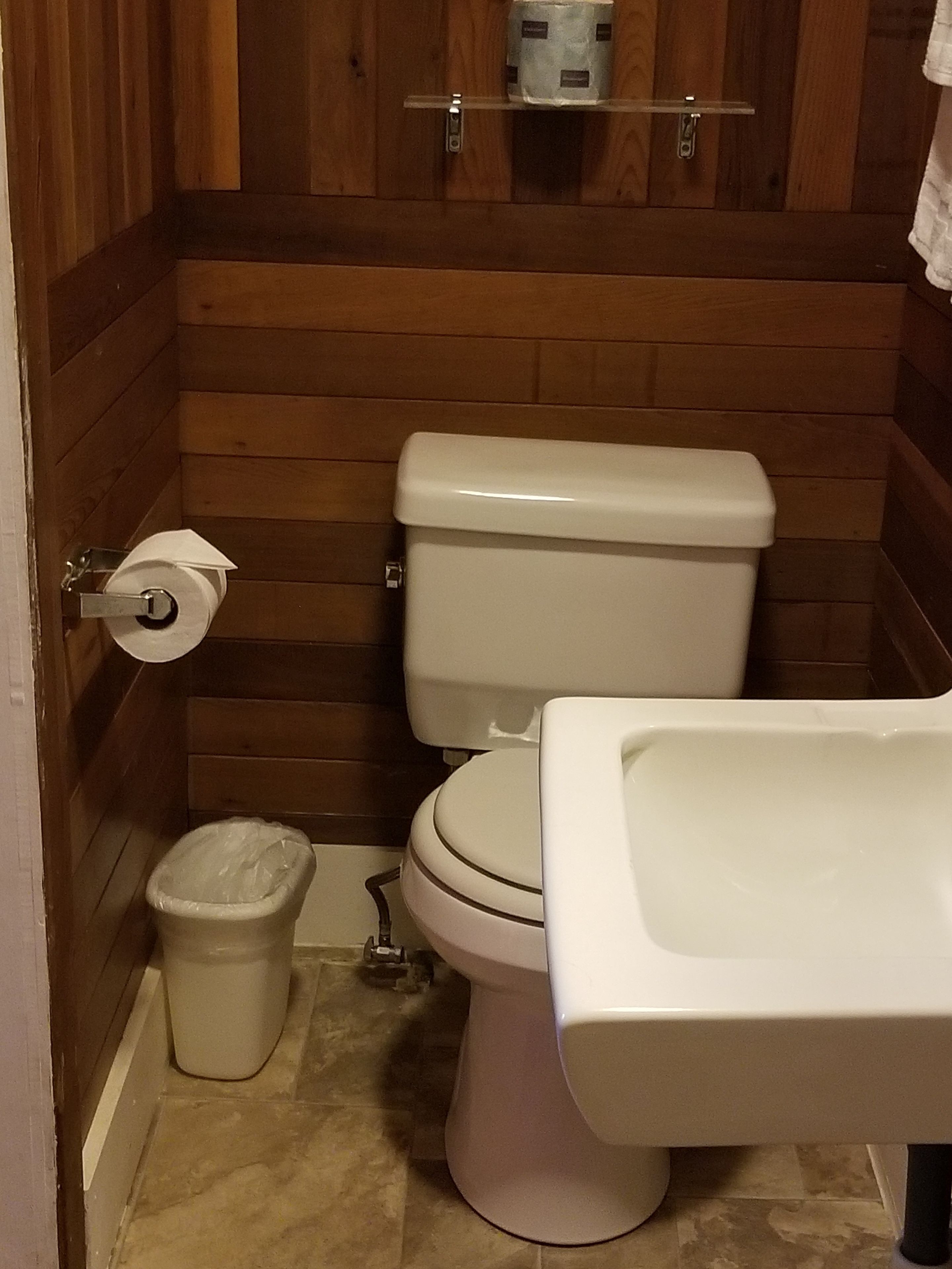 A small bathroom with a toilet, a sink, and a trash can.