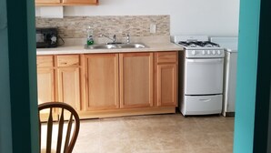 A kitchen with wooden cabinets, a sink, a stove, and a microwave.