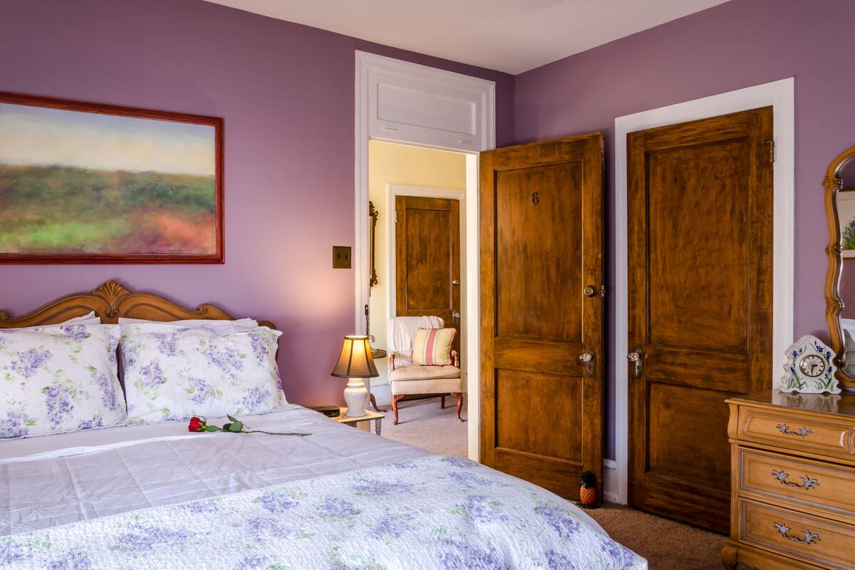 Ein Schlafzimmer mit Bett, Stuhl, Kommode und Tür.