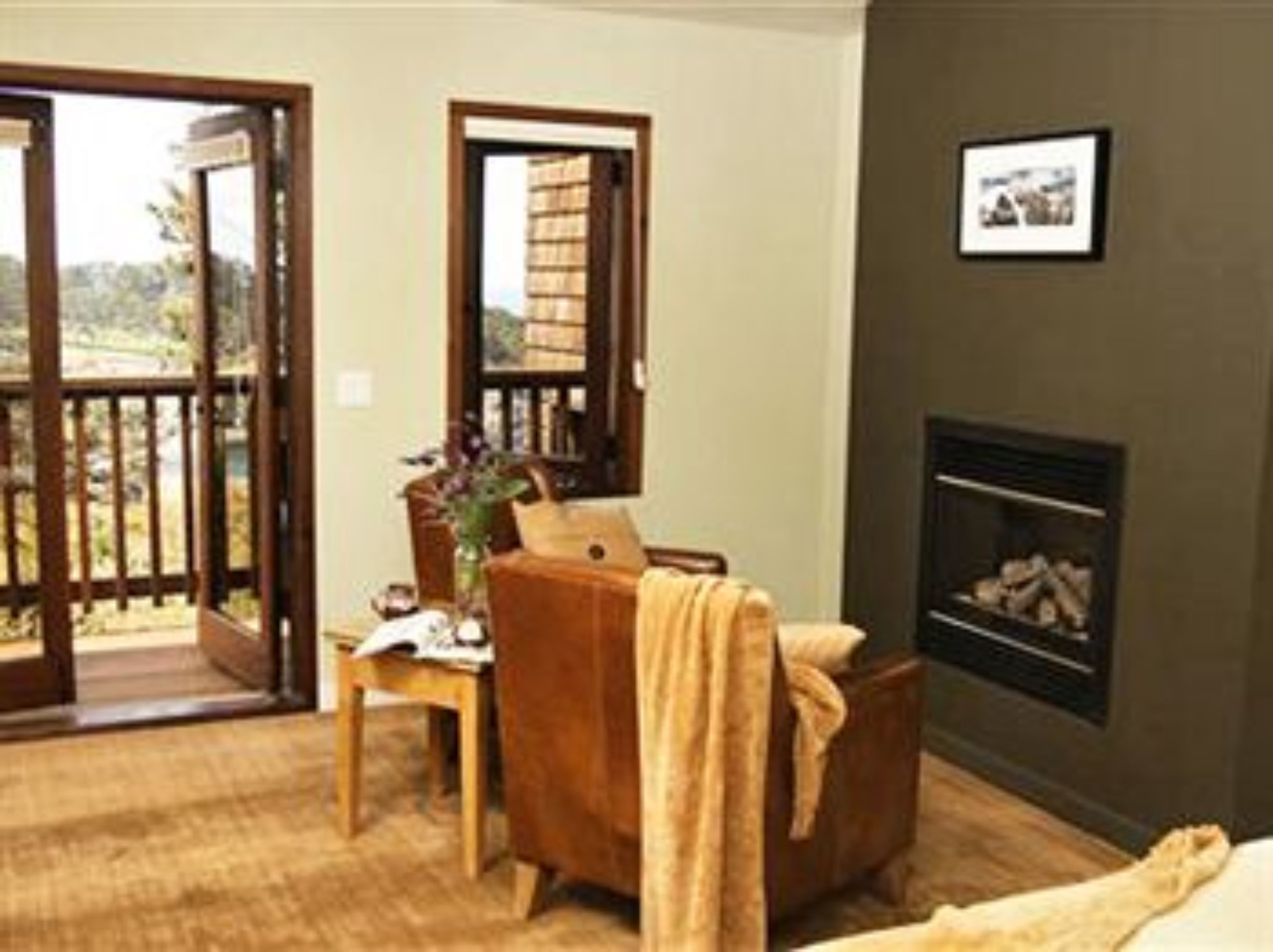 Una habitación acogedora con chimenea, una silla de madera, una mesita y vistas a través de una puerta abierta.