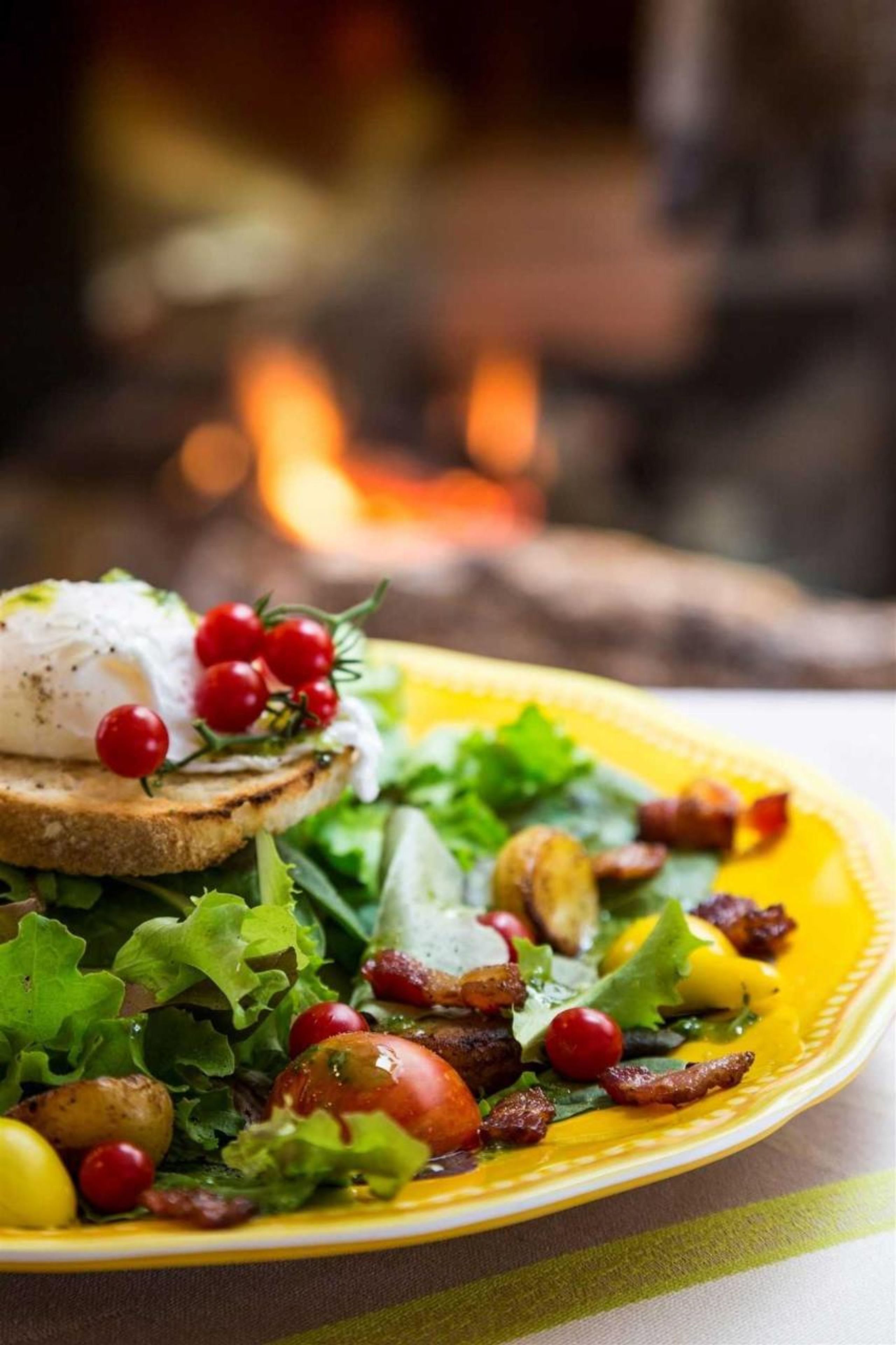 A plate of food with a poached egg, greens, and bacon.