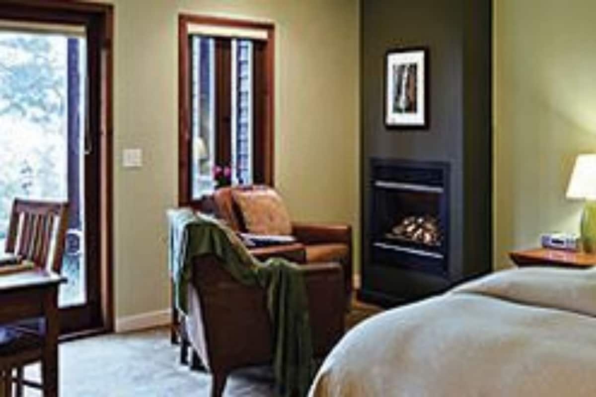 A hotel room with a bed, a chair, a fireplace, and a nightstand.