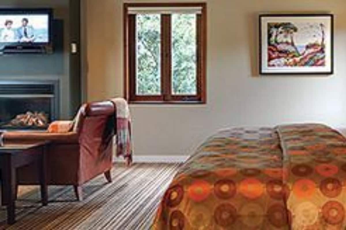 A hotel room with a bed, a desk, a chair, a television, and a window.
