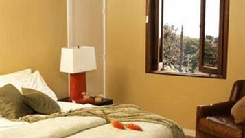 Une chambre à coucher avec un lit, une chaise, une fenêtre donnant sur un beau paysage et une lampe.
