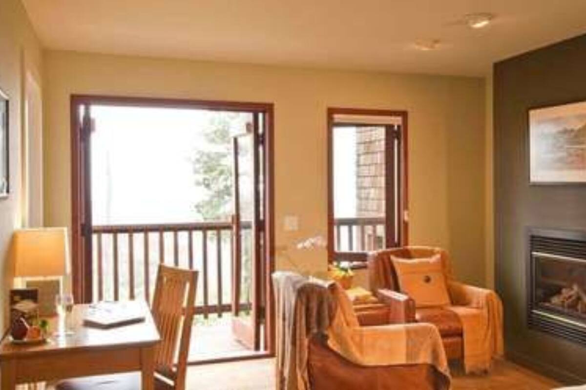 A cozy room with a fireplace, a dining table with chairs, and a balcony with a view.