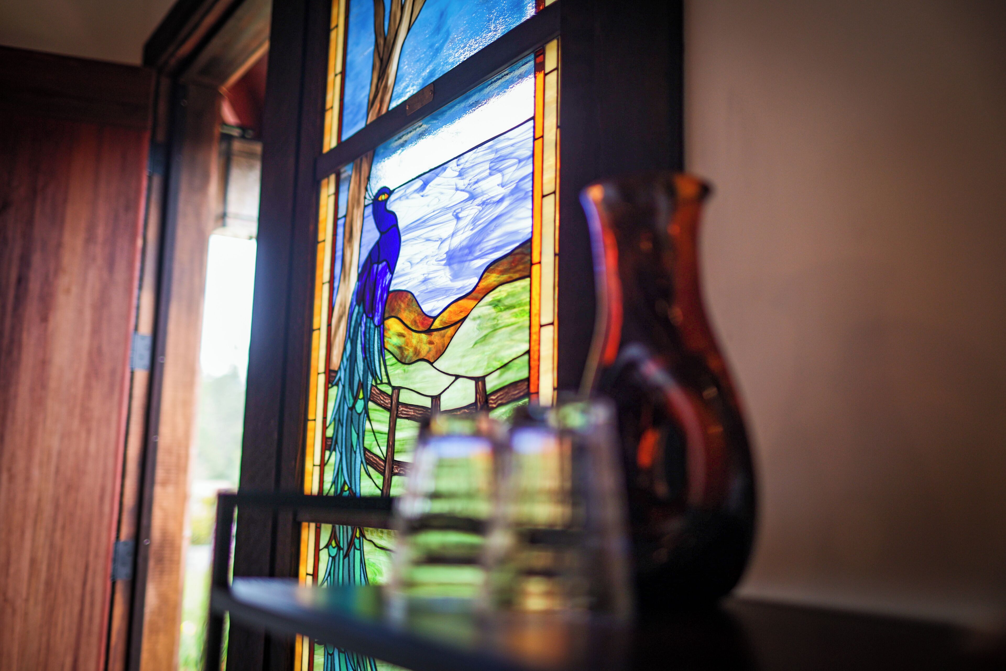 A stained glass window with a bird and landscape scene.