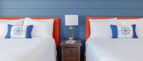 Un lit double avec une literie blanche et des oreillers bleus, une table de chevet avec une lampe, et un mur bleu.