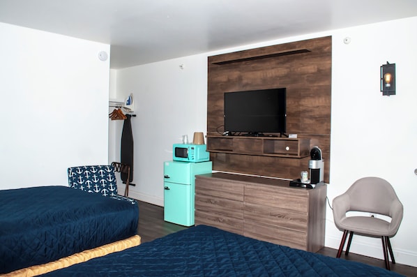 A hotel room with two beds, a TV, a microwave, a coffee maker, and a chair.