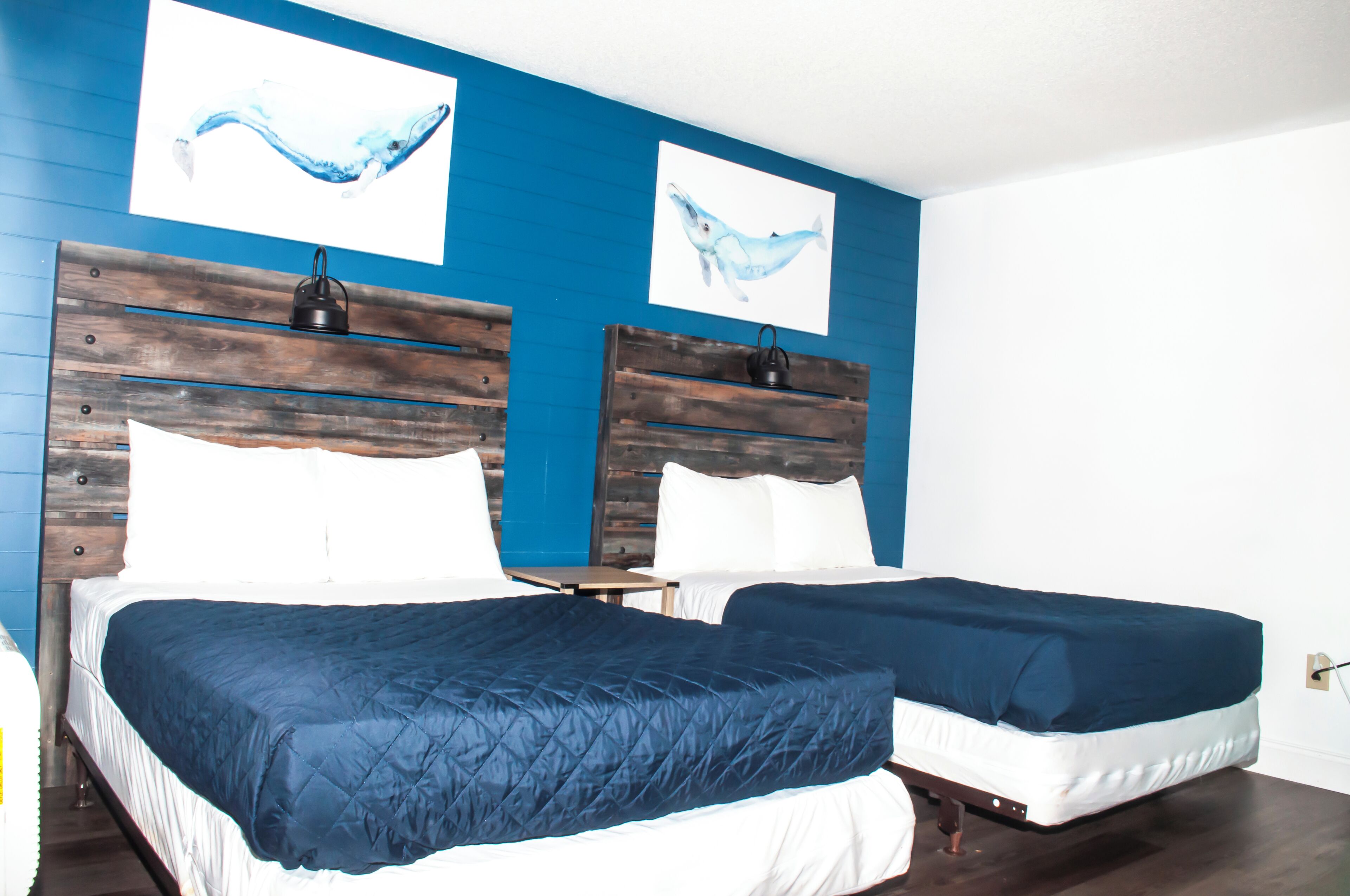 A room with two beds, each with a wooden headboard and white bedding.