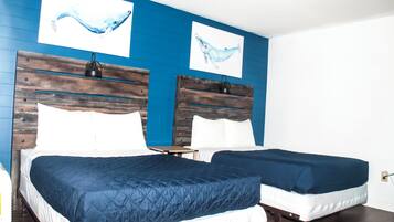 Quarto com duas camas, cada uma com cabeceira de madeira e roupa de cama branca.
