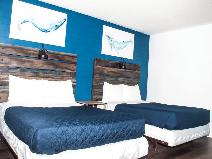 A room with two beds, each with a wooden headboard and white bedding.