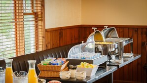 A buffet setup with various food items and beverages, including a fruit bowl, yogurt containers, and a juice dispenser. - Flagship Inn and Suites (Boothbay Harbor)