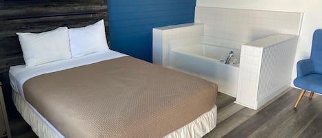 Un dormitorio con cama, una bañera blanca y una silla azul.
