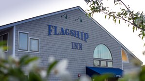 The exterior of Flagship Inn with a prominent sign, a large window, and a blue awning. - Flagship Inn and Suites (Boothbay Harbor)