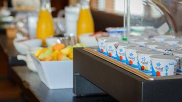 A buffet with various food items and beverages, including fruit, yogurt, and orange juice.