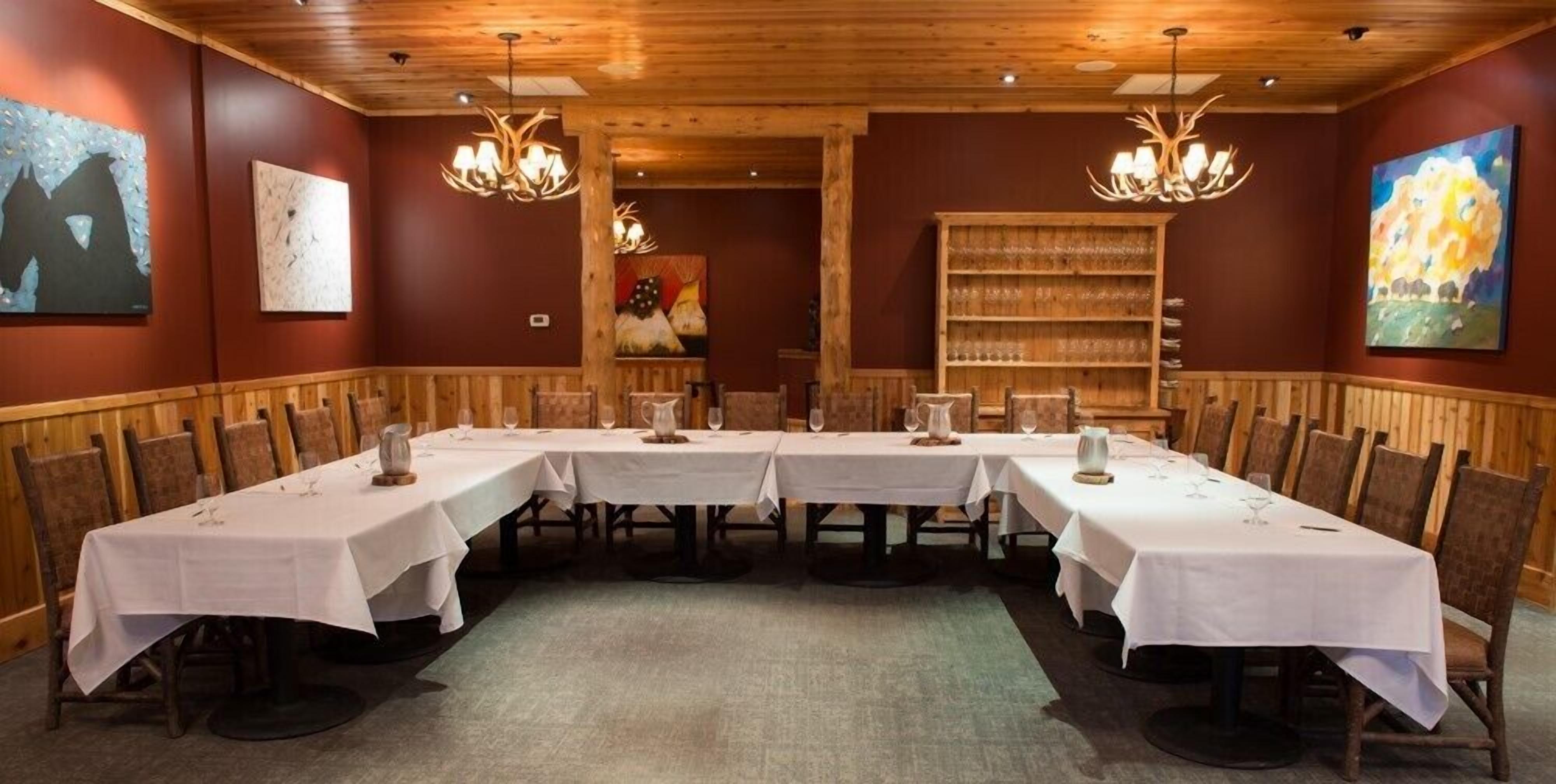 A conference room with a long table set for a meeting, wooden paneling on the walls, and a bookshelf with books and decorative items.