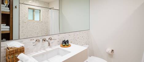 A modern bathroom with a large sink, a toilet, and a shower area.
