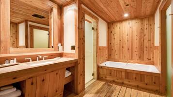 A wooden bathroom with two sinks, a large mirror, and a walk-in shower.