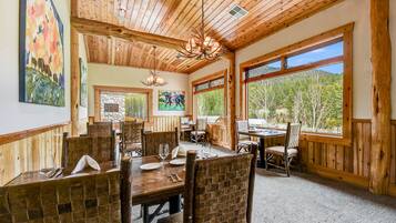 A dining area with wooden walls and ceiling, large windows, and rustic decor.